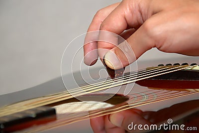 Playing acoustic guitar: hand with pick on strings
