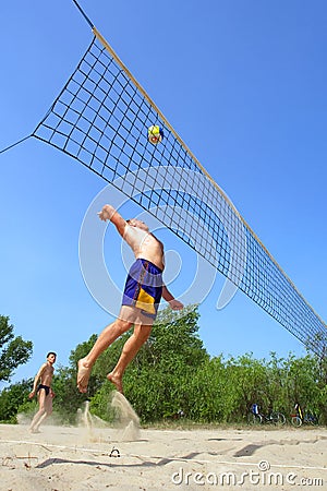 Playing beach volleyball - fat man jumps high to spike the ball