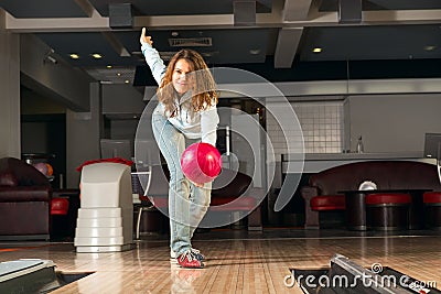Pleasant young woman throws a bowling ball