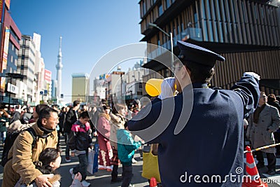 Police man conducting thousand of people to the the Asakusa Kann