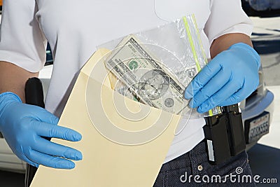 Police Officer Putting Money In Evidence Envelope