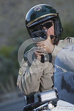 Policeman Monitoring Speed Through Radar While Sitting On Bike