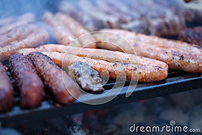 Pork and beef sausages cooking over the hot coals on a barbecue