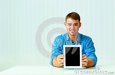 Portait of a young businessman shows the tablet computer screen