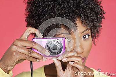 Portrait of an African American woman taking picture from camera over colored background