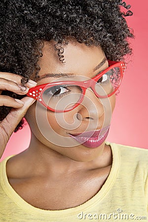 Portrait of an African American woman wearing retro glasses over colored background