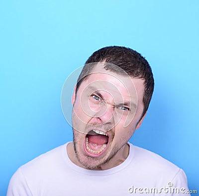 Portrait of angry man screaming and pulling hair against blue ba