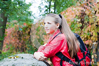 Portrait of a beautiful girl with a backpack near the stone