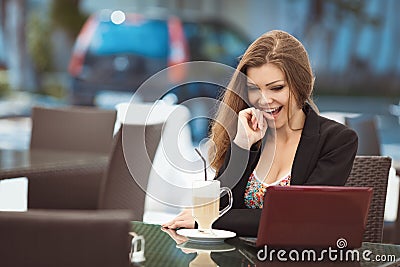 Portrait of beautiful smiling woman sitting in a cafe with laptop outdoor