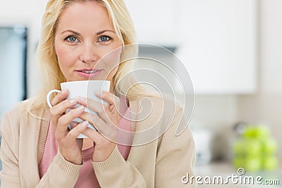 Portrait of a beautiful woman with coffee cup in kitchen
