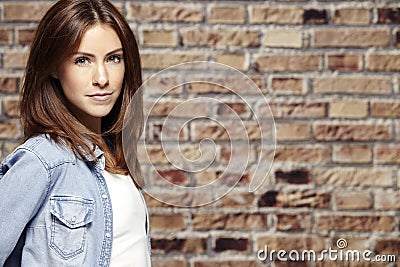 Portrait of a beautiful young woman, against brick wall