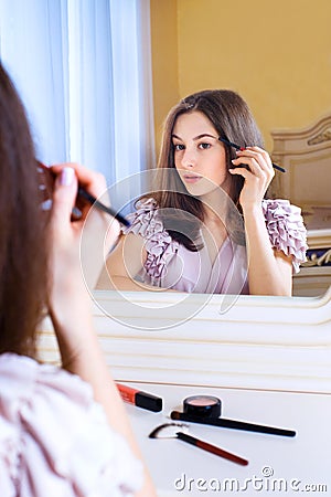 Portrait of beautiful young woman looking at the mirror