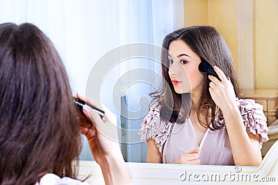 Portrait of beautiful young woman looking at the mirror