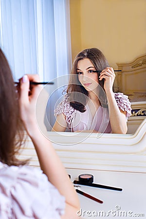 Portrait of beautiful young woman putting on makeup