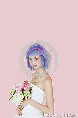 Portrait of beautiful young woman in wedding dress with dyed hair against pink background