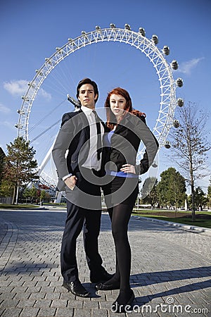 Portrait of confident young business couple standing together against London Eye, London, UK