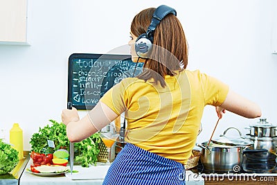 Portrait of cooking woman in kitchen. Girl standing back