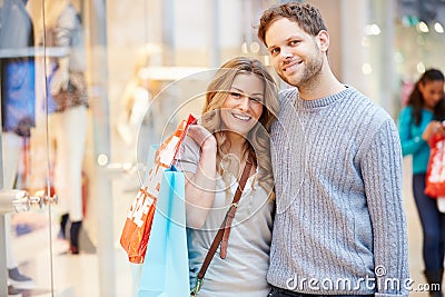 Portrait Of Couple Carrying Bags In Shopping Mall