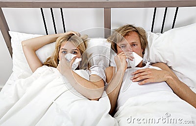 Portrait of couple suffering from cold lying on bed