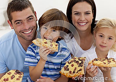 Portrait of family eating pizza in living-room