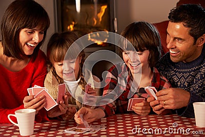 Portrait Of Family Playing Cards By Cosy Log Fire