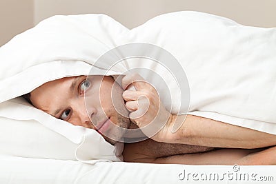 Portrait of funny scared Young man in bed