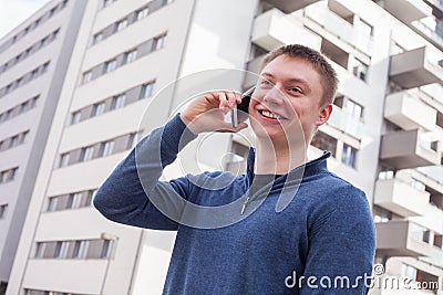 Portrait of handsome happy man in urban background talking on ph