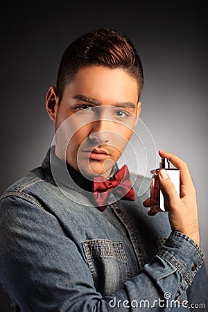 A portrait of a handsome male applying perfume
