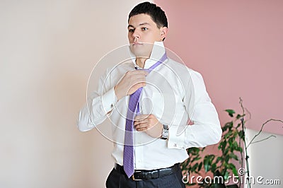 Handsome stylish young man tie a tie