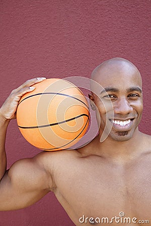 Portrait of a happy African American man with basketball on shoulder over colored background