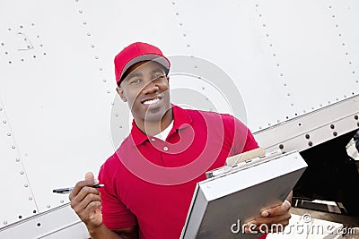 Portrait of a happy African American man holding clipboard with delivery truck in background