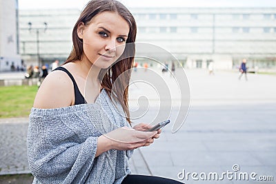 Portrait of a happy fashion woman with mobile phone. In a backgr