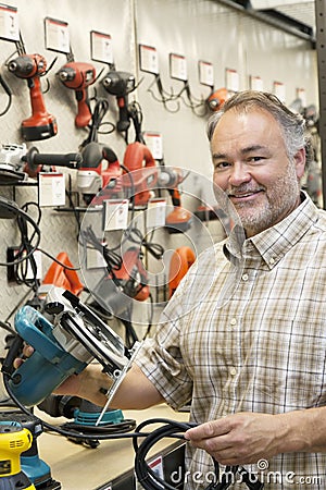 Portrait of a happy hardware store owner with electric saw