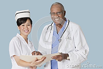 Portrait of happy health care professionals with medical report over light blue background