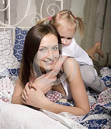 Portrait of happy mother and daughter in bed hugging and smiling