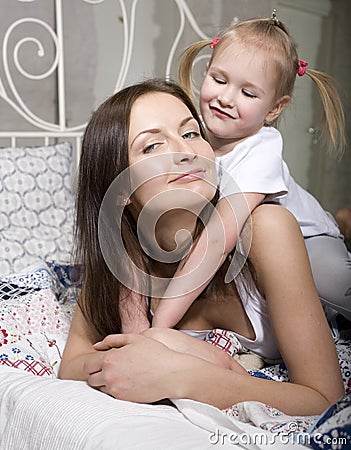 Portrait of happy mother and daughter in bed hugging and smiling