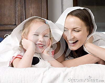 Portrait of happy mother and daughter in bed hugging and smiling