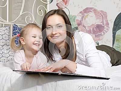 Portrait of happy mother and daughter in bed hugging and smiling