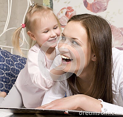 Portrait of happy mother and daughter in bed hugging and smiling