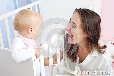 Portrait of a happy mother laughing with cute baby in crib