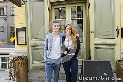 Portrait of happy owners standing in front of restaurant