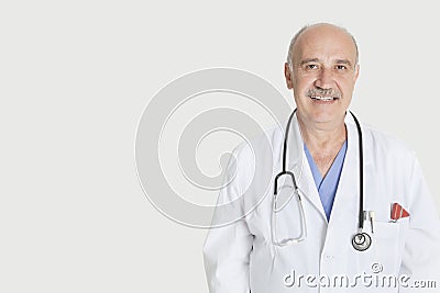 Portrait of happy senior medical practitioner over gray background