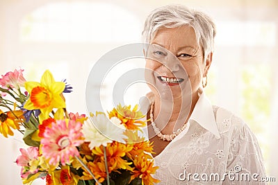 Portrait of happy senior woman holding flowers