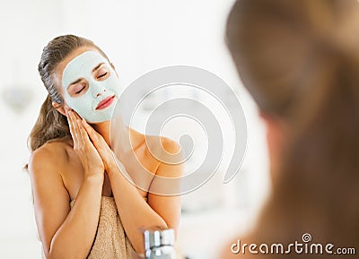 Portrait of happy young woman with cosmetic mask on face