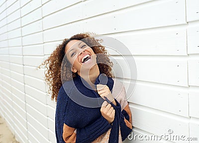 Portrait of a happy young woman holding sweater and laughing outdoors