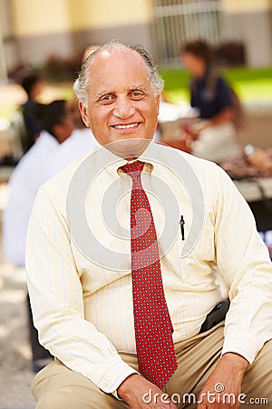 Portrait Of High School Teacher Sitting On School Campus