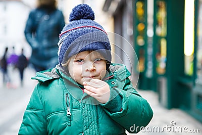 Portrait of little toddler boy walking through the city on cold