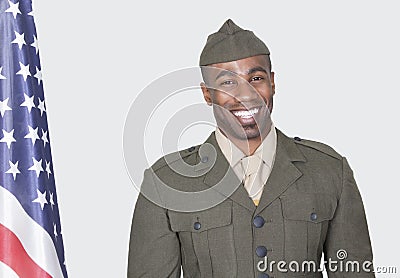 Portrait of a male US soldier smiling with American flag over gray background