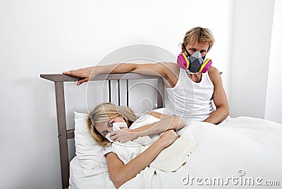 Portrait of man wearing gas mask while woman suffering from cold in bed