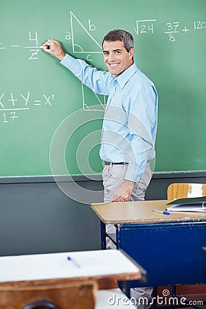 Portrait Of Mature Teacher Writing On Board